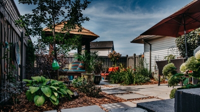 Patio with gazebo, plants, furniture, and umbrella. Photo