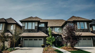 Suburban homes with brown roofs, gray siding, and garages. Photo