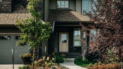 Front of house with beige door, landscaping, and walkway. Photo